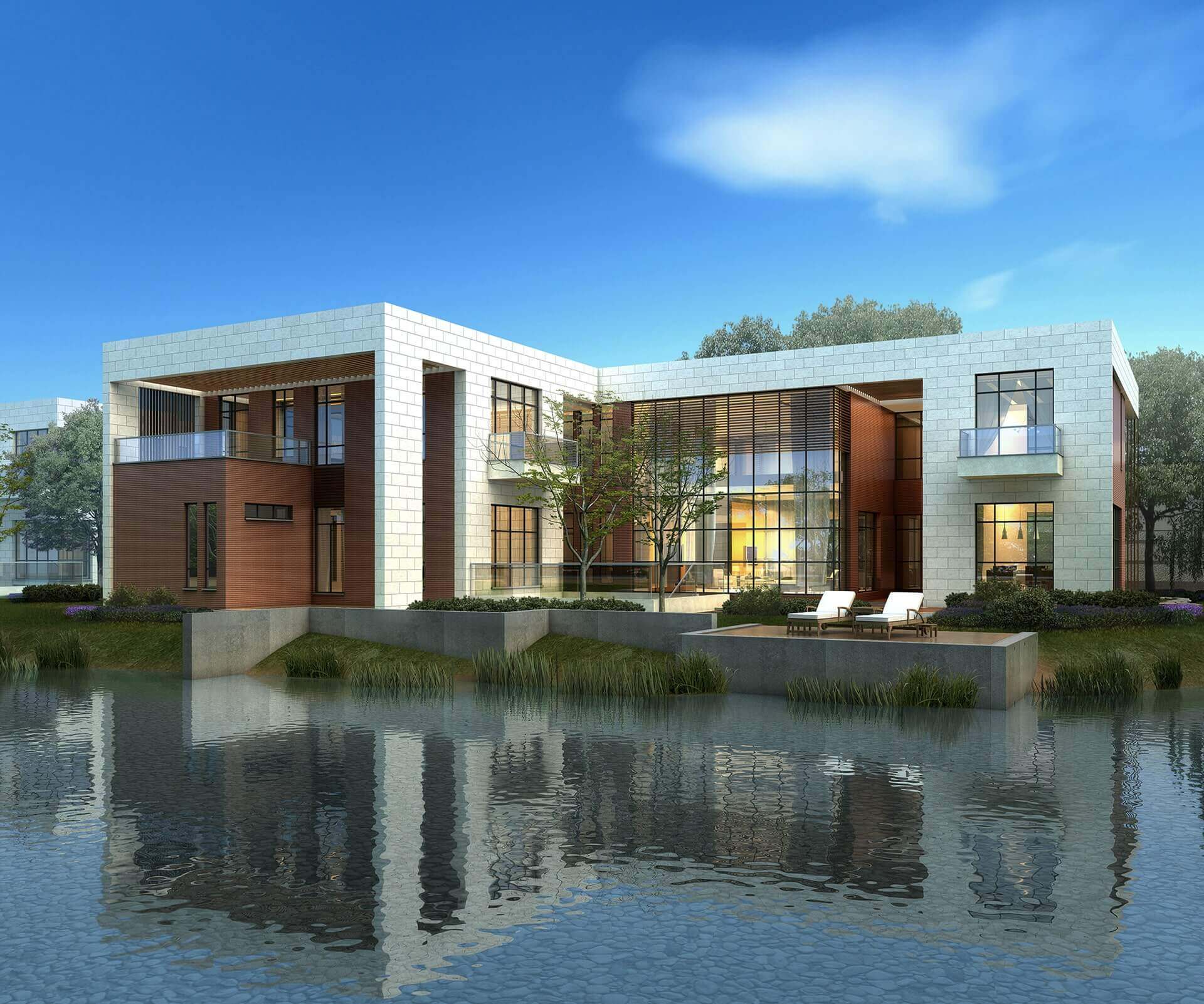 Modern two-story house by the water with large windows and outdoor lounge chairs.
