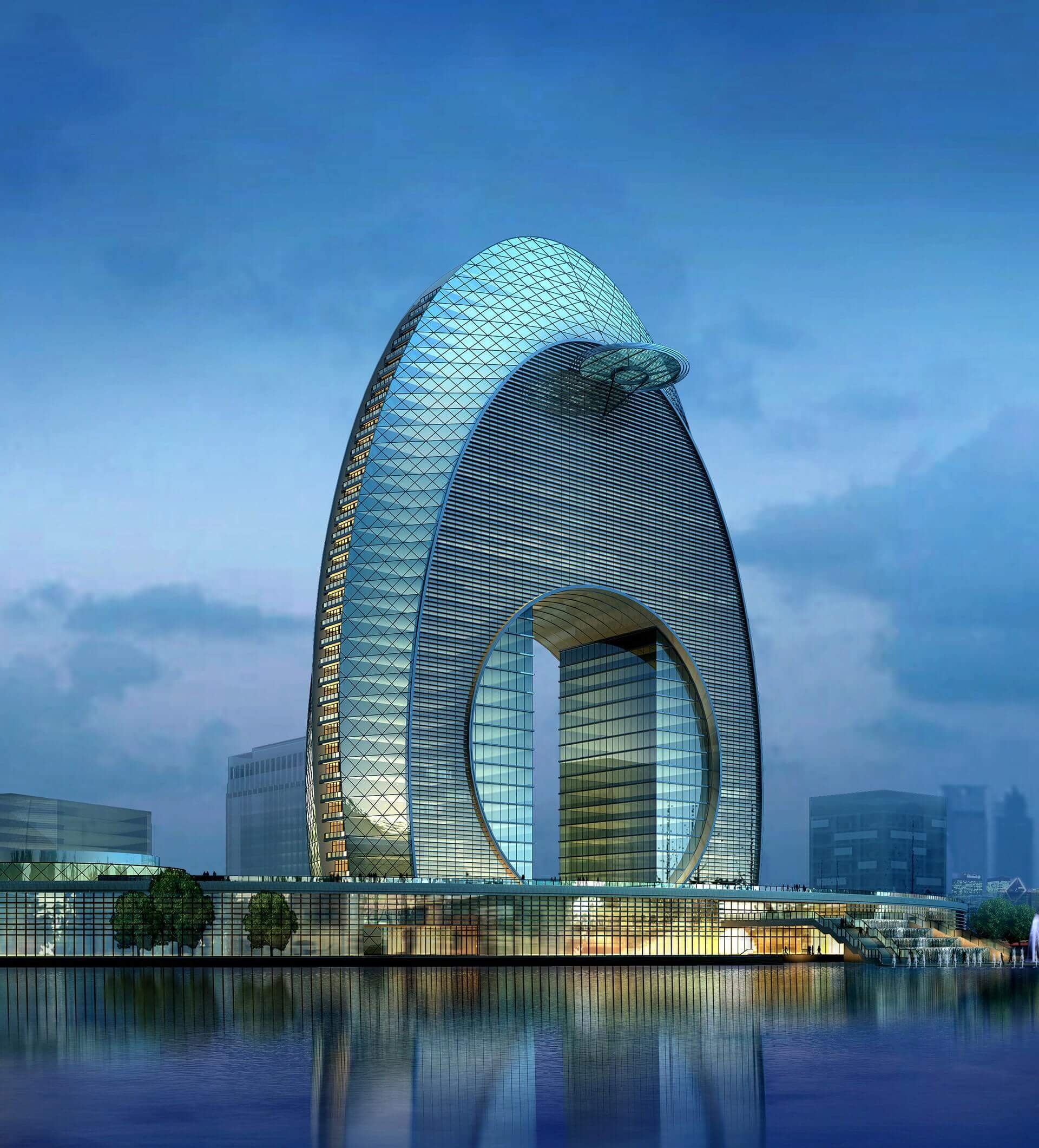 Modern, arch-shaped skyscraper with a large circular opening, reflecting on water at dusk.