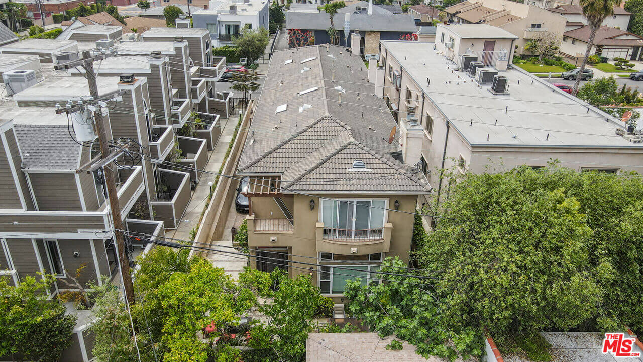 Aerial view of residential buildings with greenery and power lines.