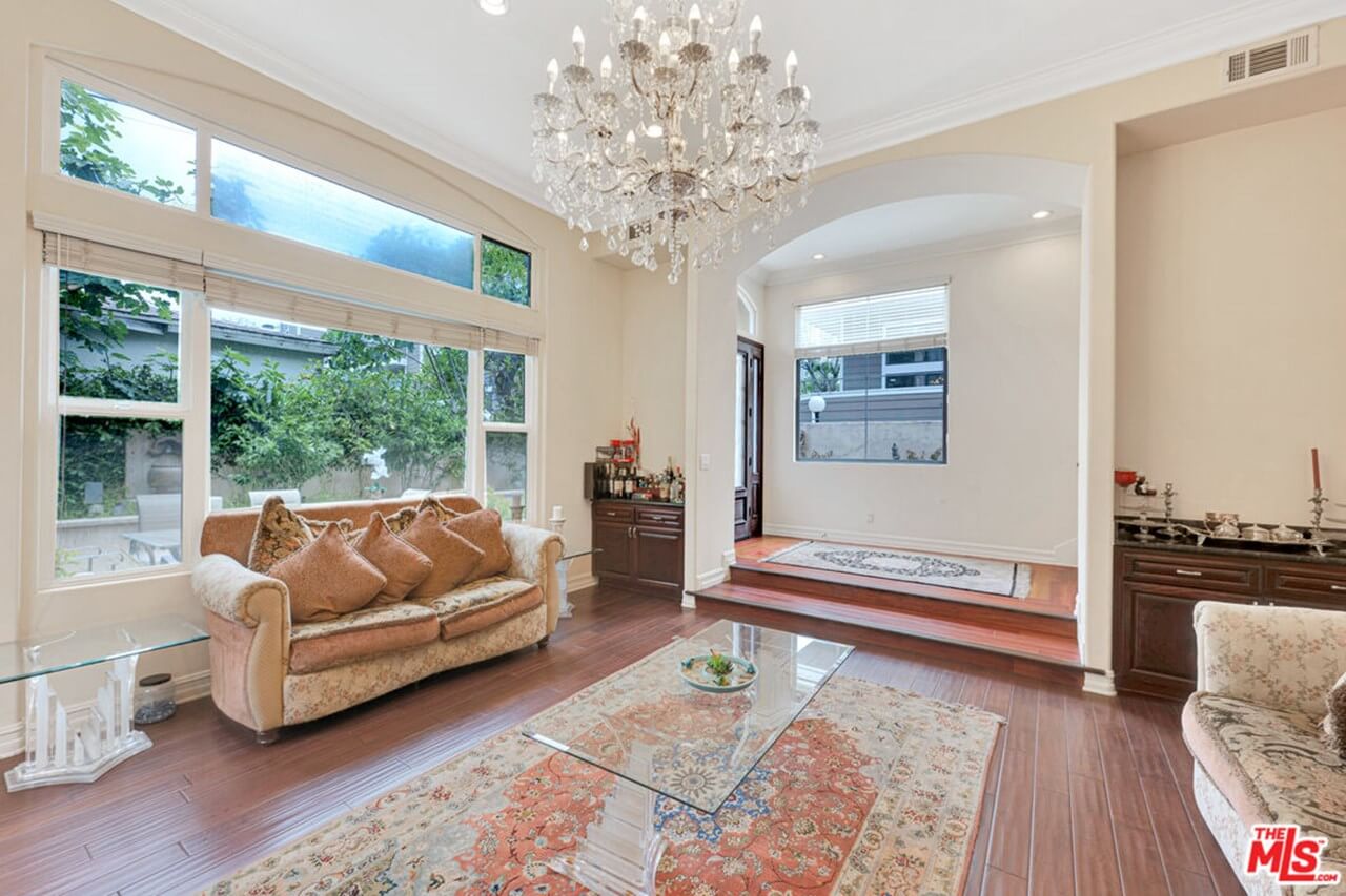 Elegant living room with crystal chandelier and large windows.