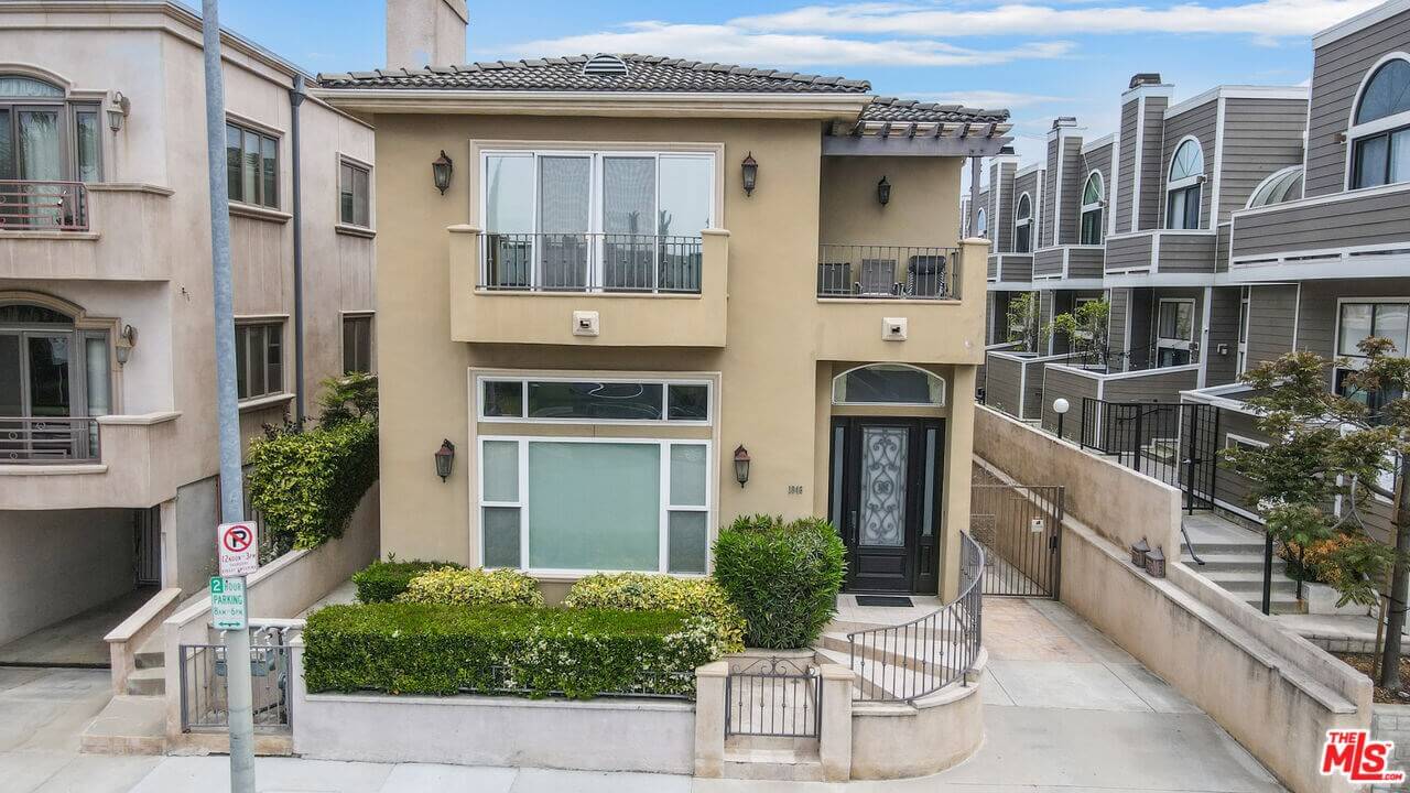 Modern two-story beige townhouse with small front garden and balcony.