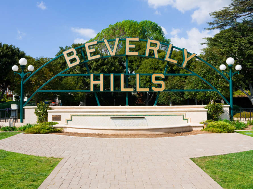 Beverly Hills sign against a clear blue sky with greenery.