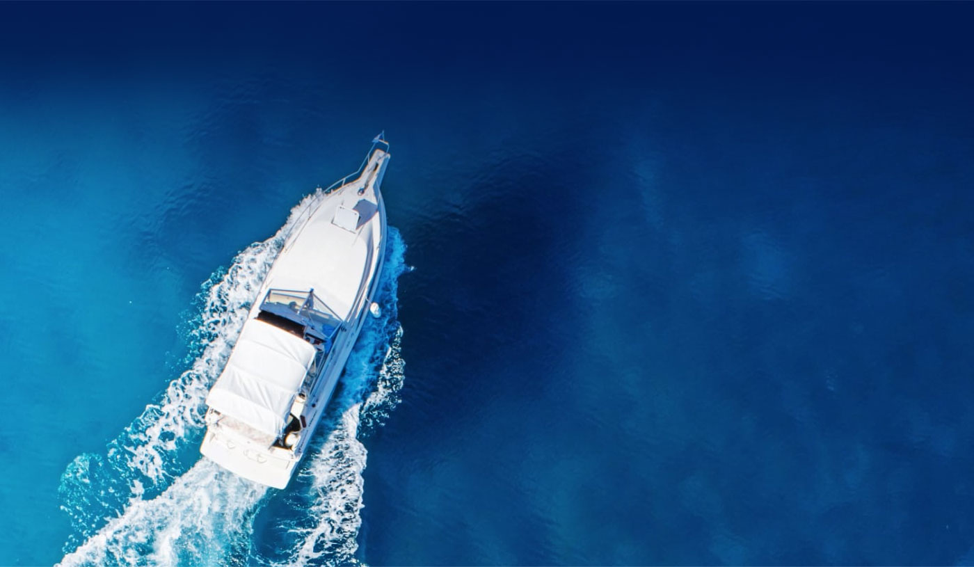 A white boat cruising through deep blue water leaving a trail of white foam.