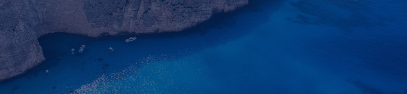 Boats near rocky cliffs in clear blue water.