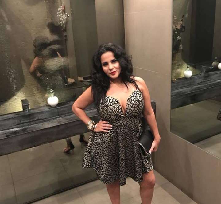 Woman in patterned dress posing in mirror.
