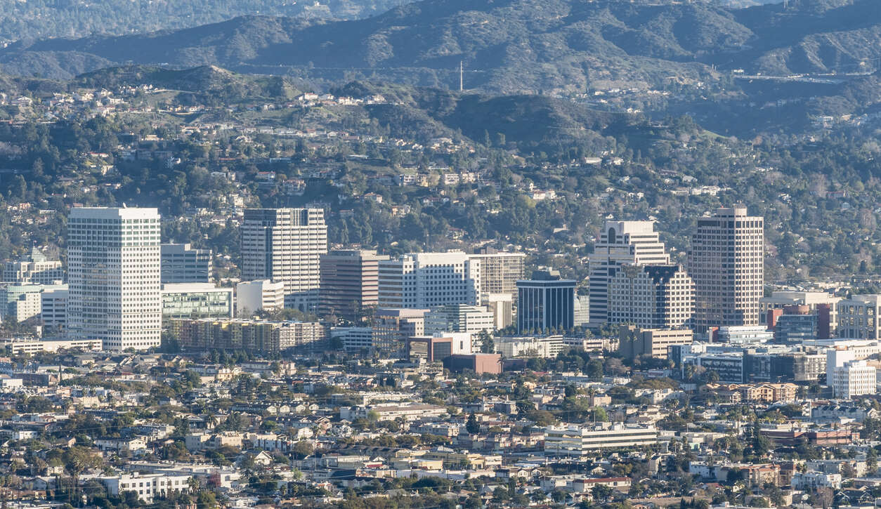 A sprawling cityscape with mountains in the background under a clear sky.