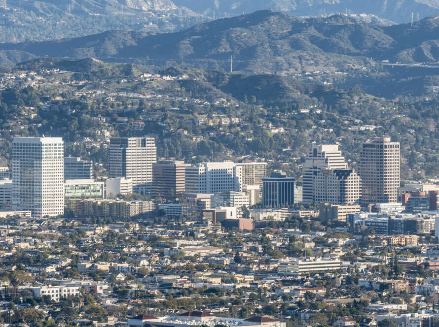 A sprawling cityscape with mountains in the background under a clear sky.
