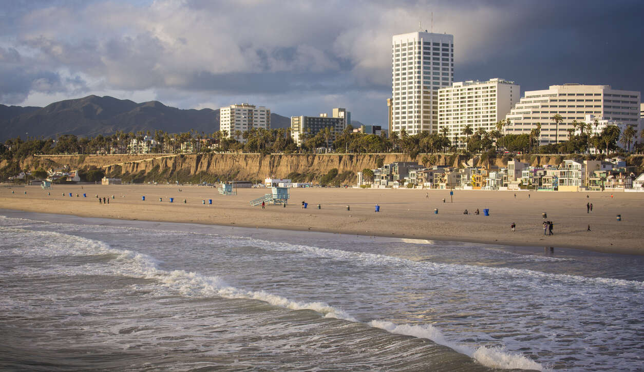 Beachfront with tall buildings and people enjoying the sunny shore.