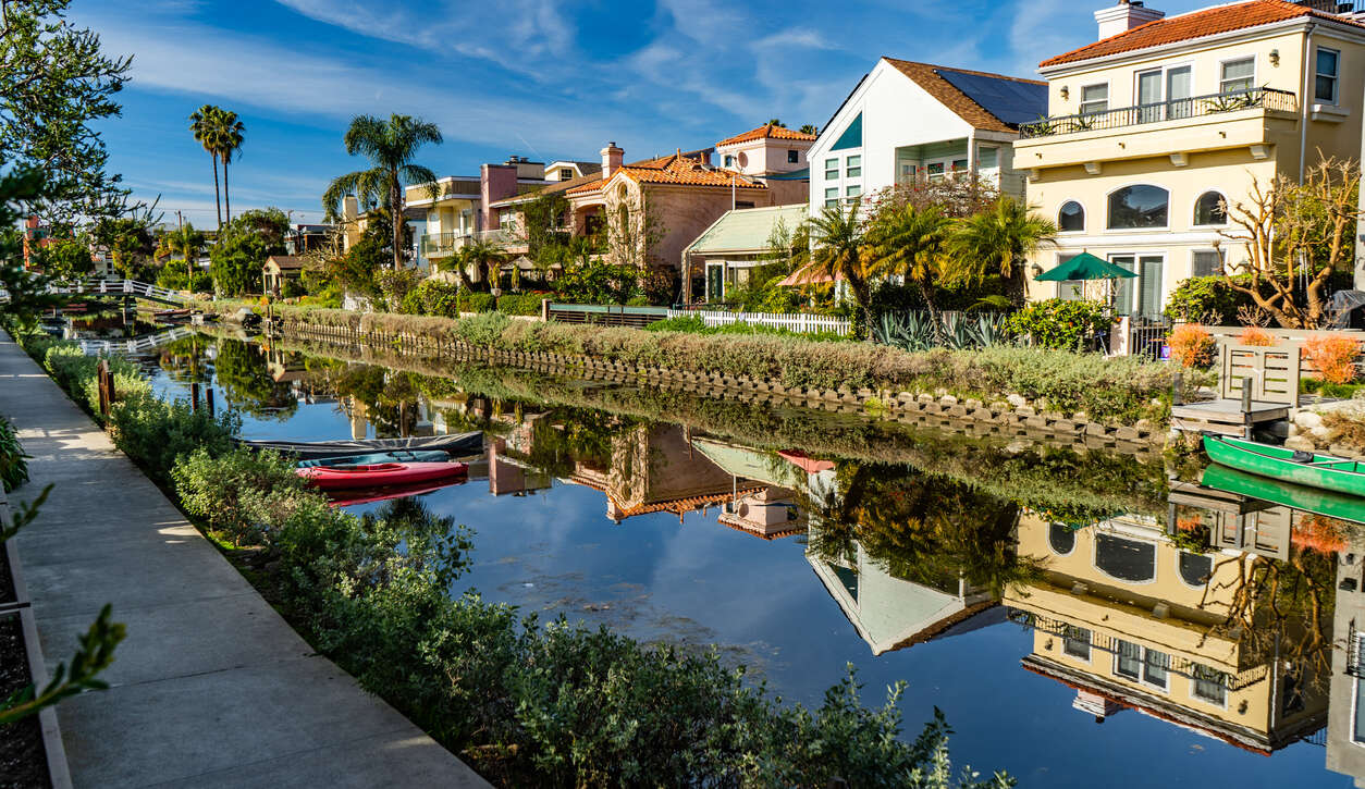 Colorful houses reflecting on a calm canal with boats docked along the shore.