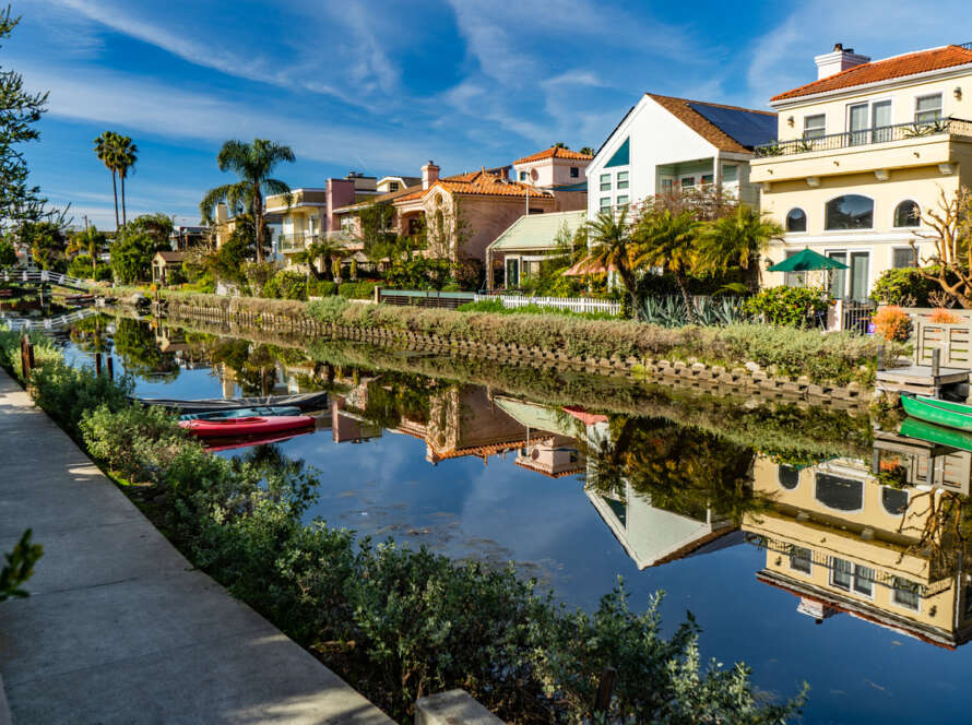 Colorful houses reflecting on a calm canal with boats docked along the shore.