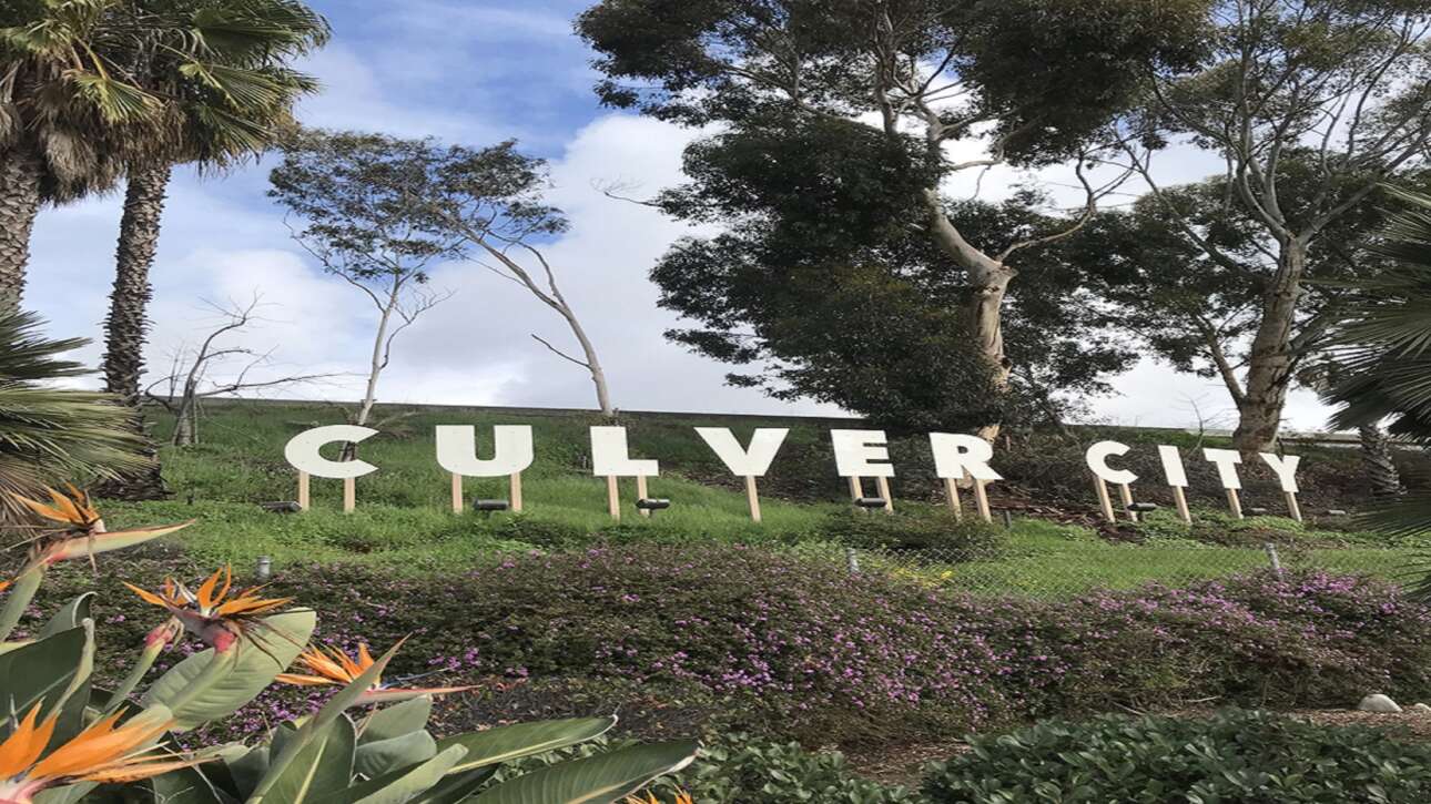Large white letters spelling 'GULYVER CITY' on a grassy hillside with trees behind.