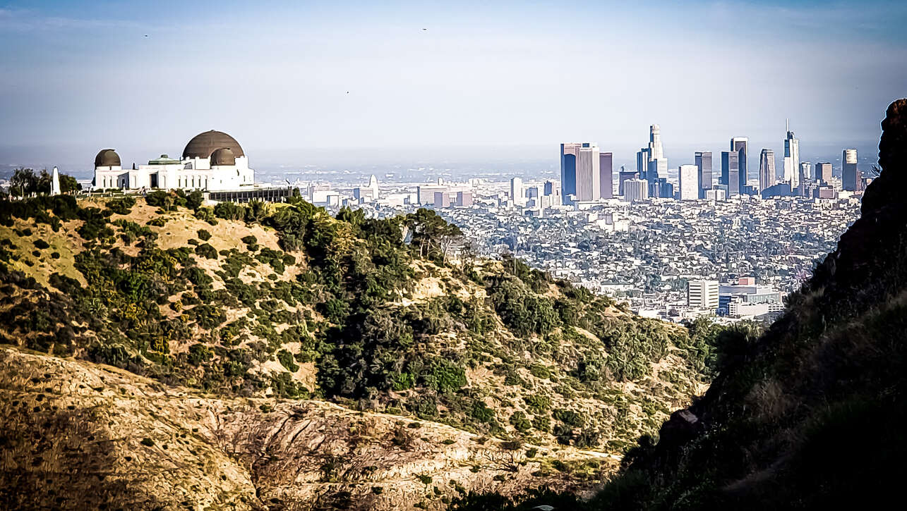 View of a city skyline from a hilltop with a clear sky.