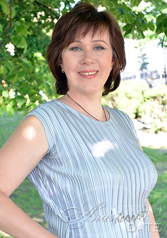 Smiling woman in blue dress outdoors.