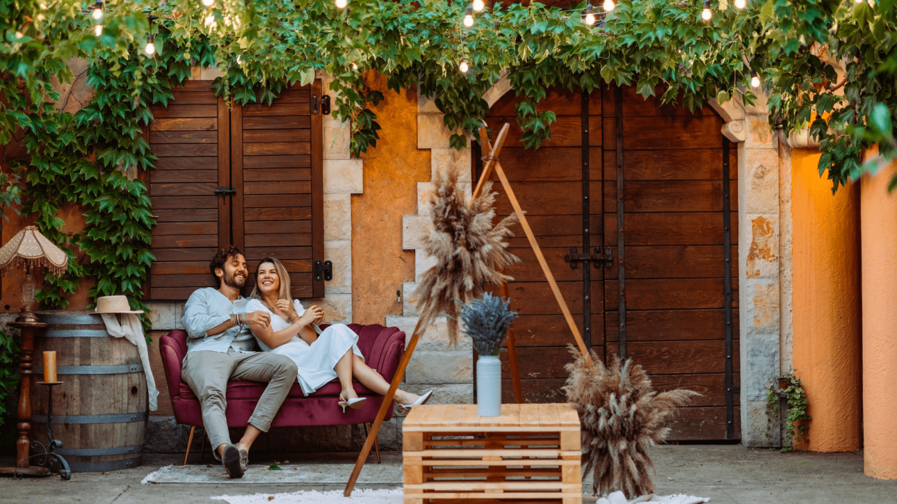 Couple enjoying a romantic outdoor moment under hanging lights and greenery.