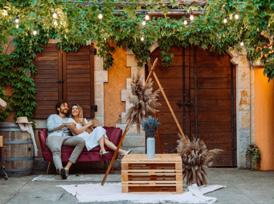 Couple enjoying a romantic outdoor moment under hanging lights and greenery.